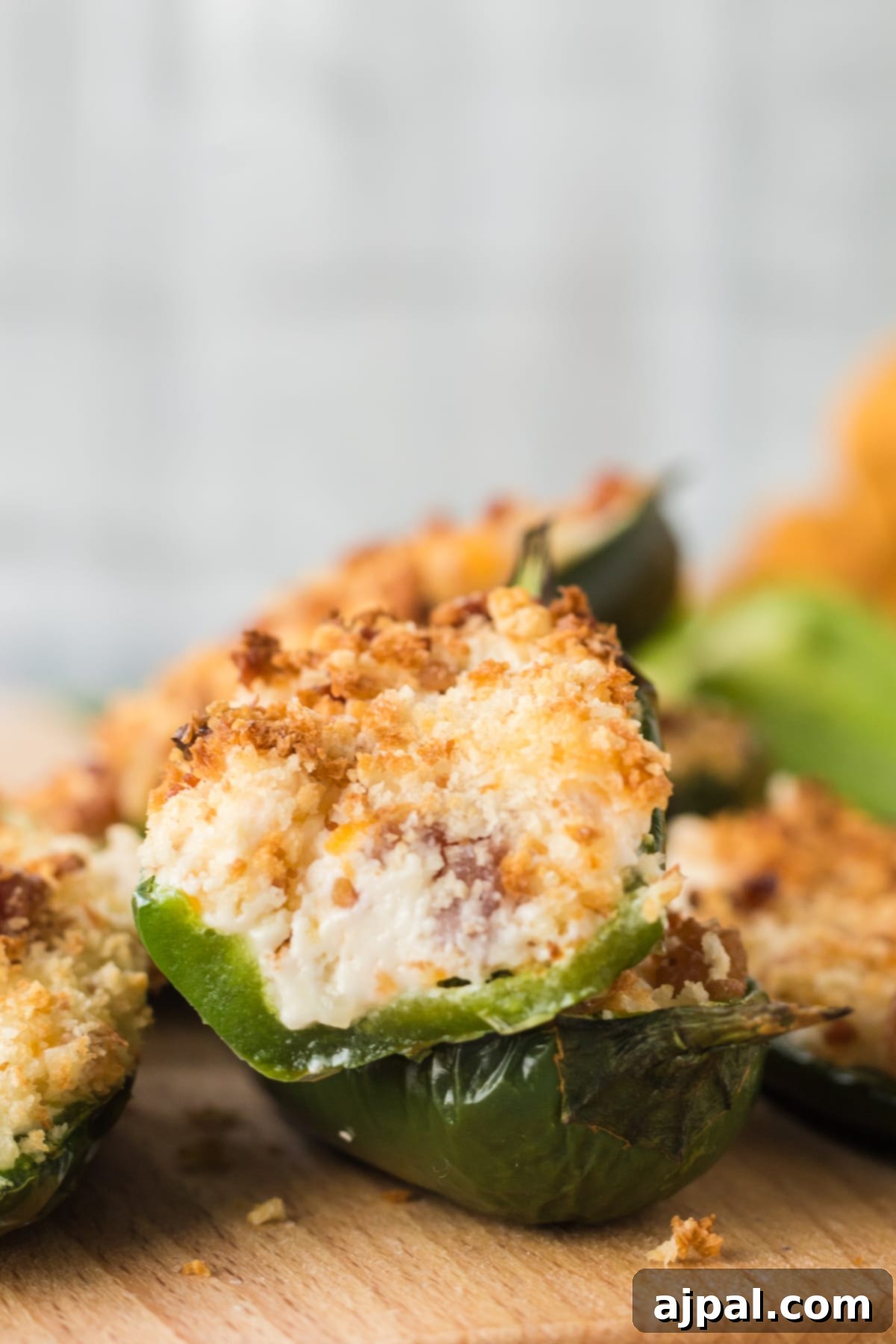 A perfectly air-fried jalapeño popper, sliced in half to reveal its creamy filling, stacked invitingly on a plate with other poppers.