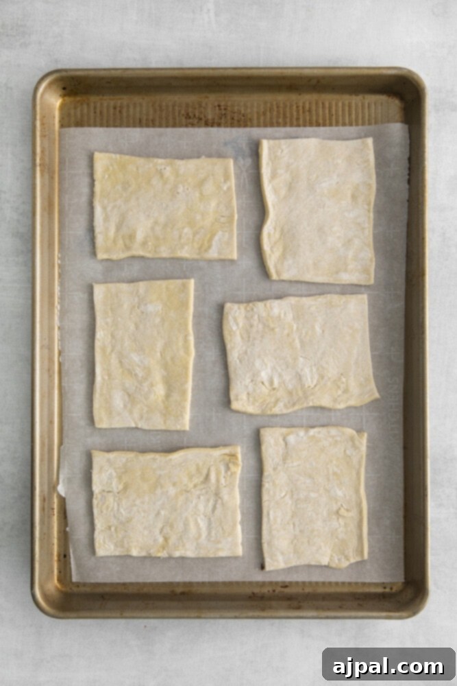 Tomato Goat Cheese Tarts 5 Six perfectly cut rectangular pieces of puff pastry arranged on a baking sheet lined with parchment paper, ready for assembly.