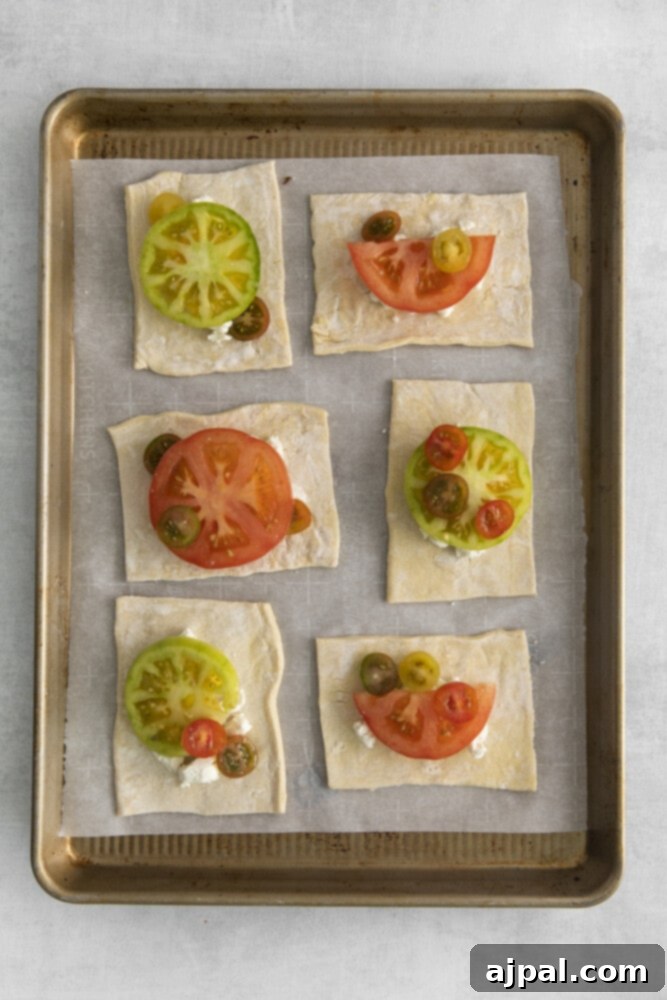 Tomato Goat Cheese Tarts 7 Sliced tomatoes artfully arranged on top of the goat cheese on each puff pastry rectangle, adding vibrant color and fresh flavor.