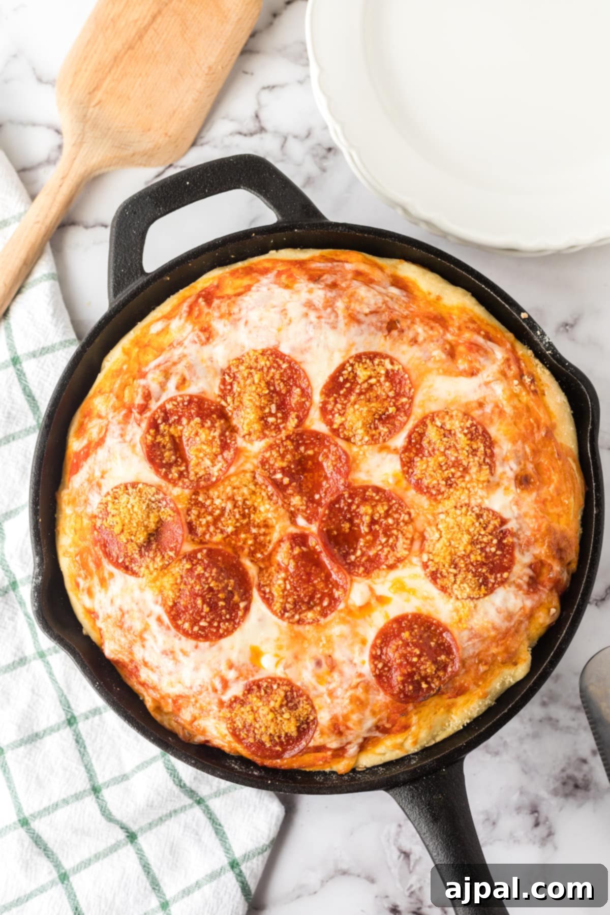 A freshly baked deep dish pizza, loaded with pepperoni, presented in a cast iron skillet on a rustic wooden table.