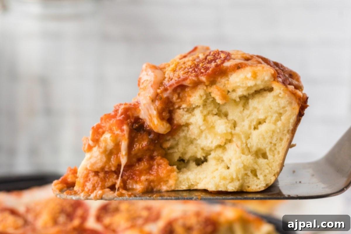 A savory slice of deep dish pizza with pepperoni, gently held on a spatula.