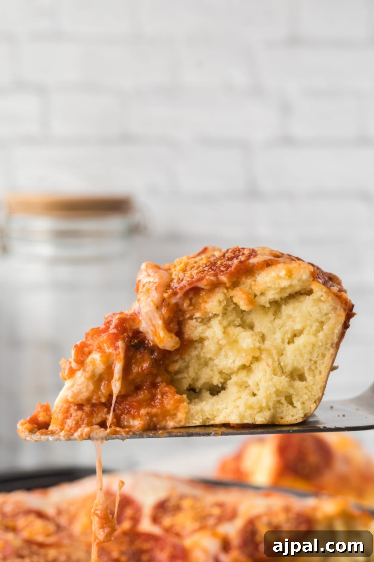 A serving of deep dish pizza, rich with sauce and melted cheese, being carefully lifted from a pan with a spatula.
