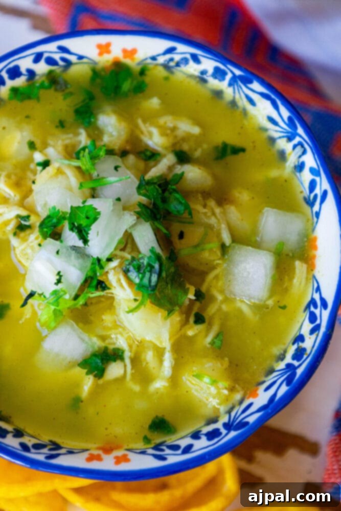 Zesty Green Chicken Posole 2 Easy green chicken posole in a blue bowl, garnished with fresh cilantro and a lime wedge.