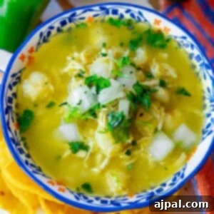 posole verde with chopped onion, cilantro, shredded chicken and hominy in a bowl