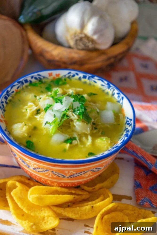A bowl of easy chicken posole verde with tortilla chips on a table.