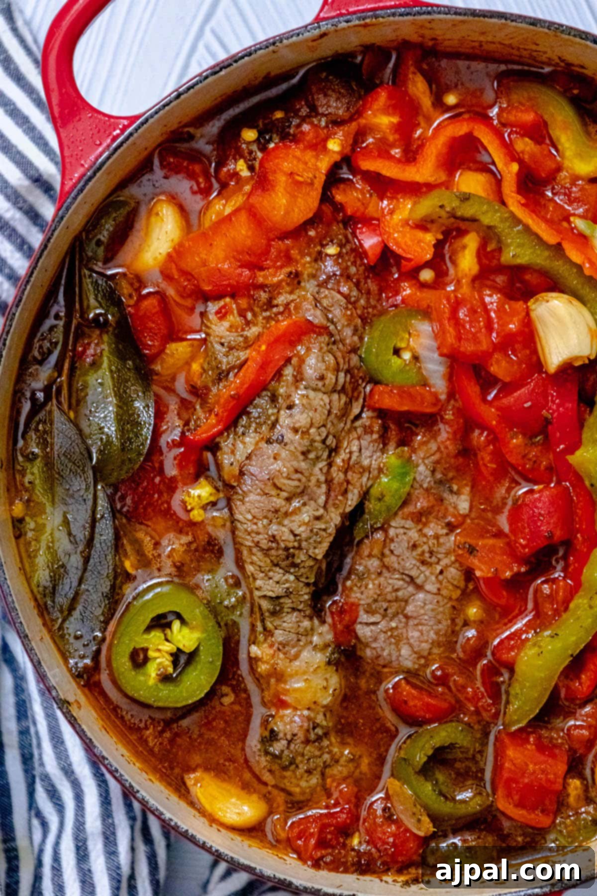Spicy Mexican Pot Roast 12 A large pot roast simmering in a Dutch oven, surrounded by tender bell peppers, onions, bay leaves, and garlic cloves, bathed in a rich, flavorful jus.