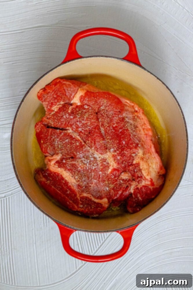 Spicy Mexican Pot Roast 6 A raw pot roast, unseasoned and ready for preparation, resting inside a cast iron Dutch oven.