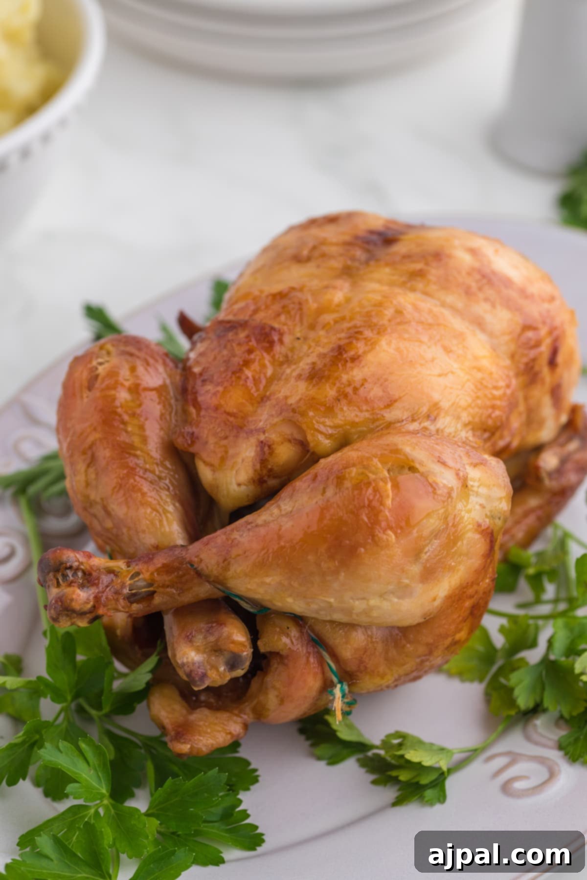 Roasted chicken leg on a white plate with parsley in front of an Instant Pot, showcasing a perfectly cooked bird ready to be enjoyed.