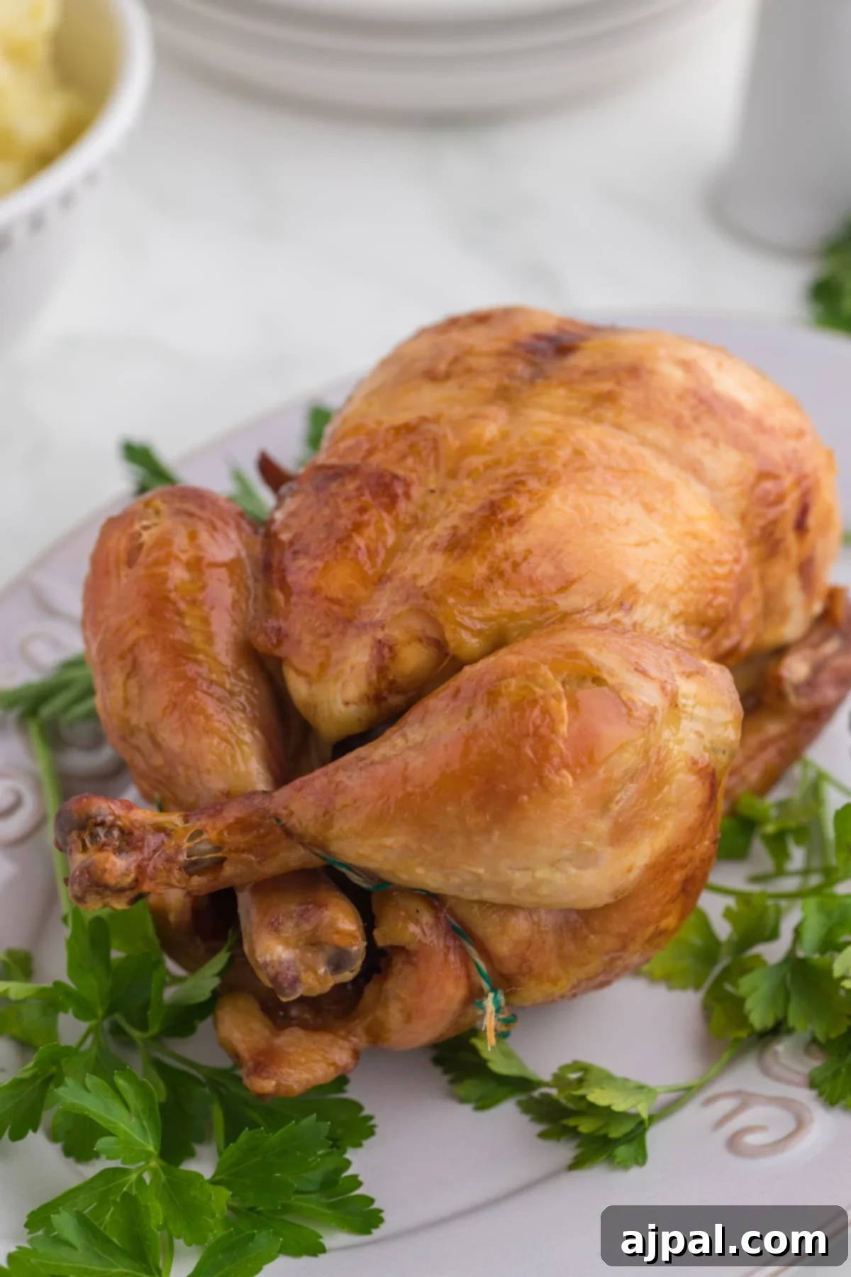Perfect Instant Pot Whole Chicken 2 roasted chicken leg on a white plate with parsley in front of an instant pot