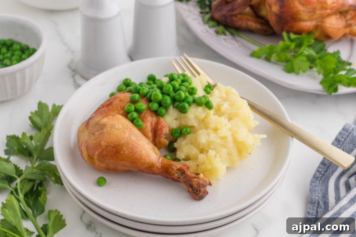 Roasted chicken leg on a white plate with peas and mashed potatoes in front of an Instant Pot, a delicious and quick meal solution.