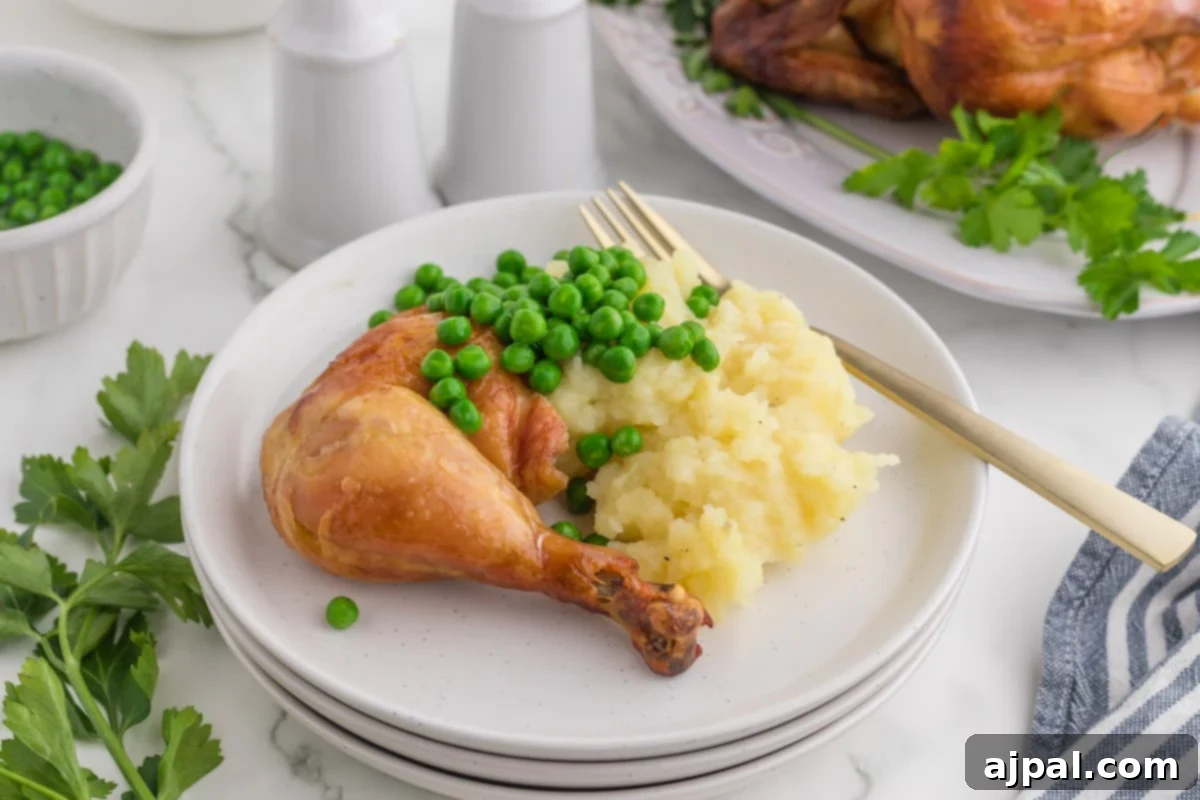 Perfect Instant Pot Whole Chicken 3 roasted chicken leg on a white plate with peas and mashed potatoes in front of an instant pot