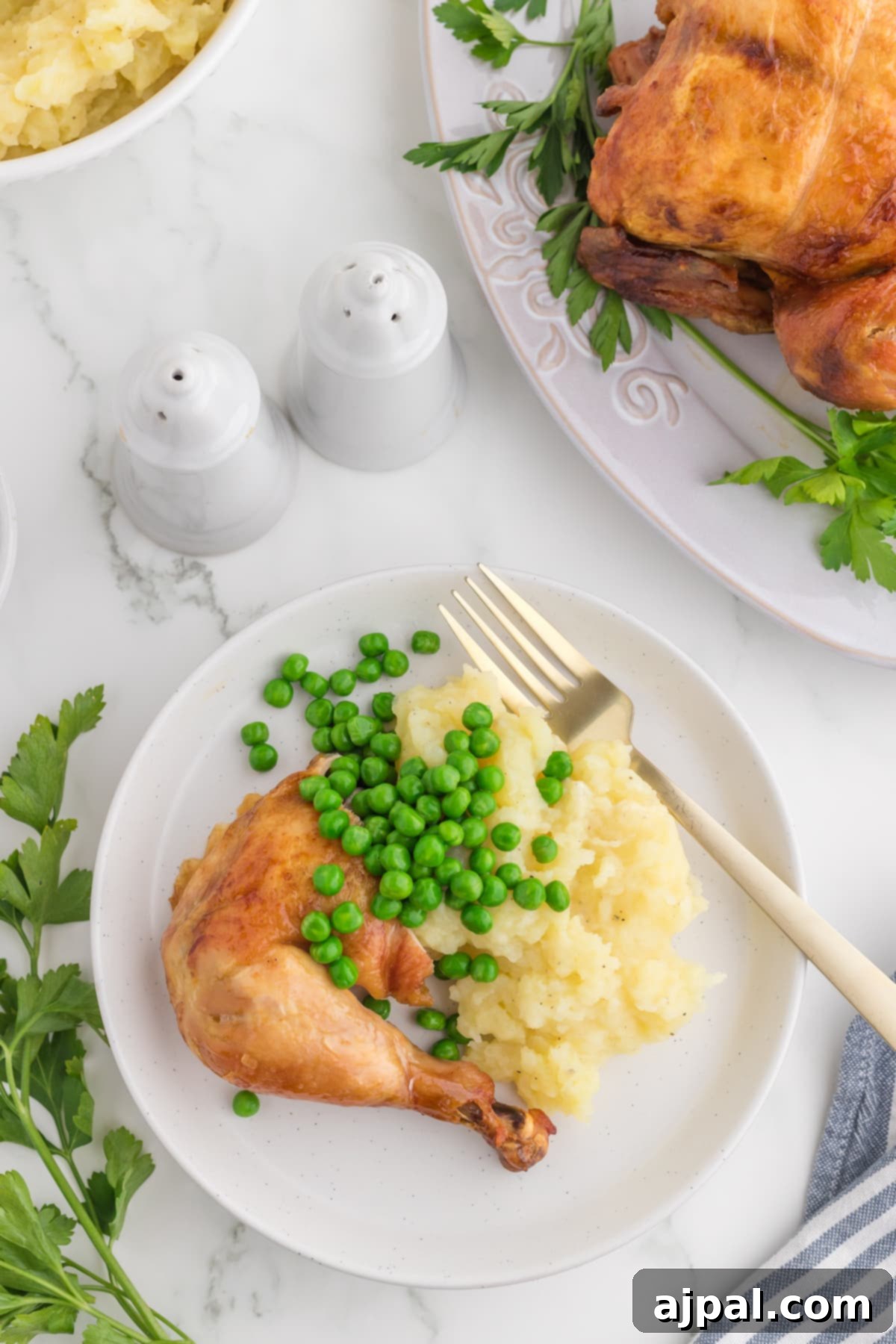Perfect Instant Pot Whole Chicken 9 roasted chicken leg on a white plate with peas and mashed potatoes in front of an instant pot