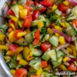 Authentic Jerusalem Salad 18 A bowl of finely chopped bell pepper, cucumber, cherry tomatoes, red onion, and parsley, perfectly diced for an Israeli salad.