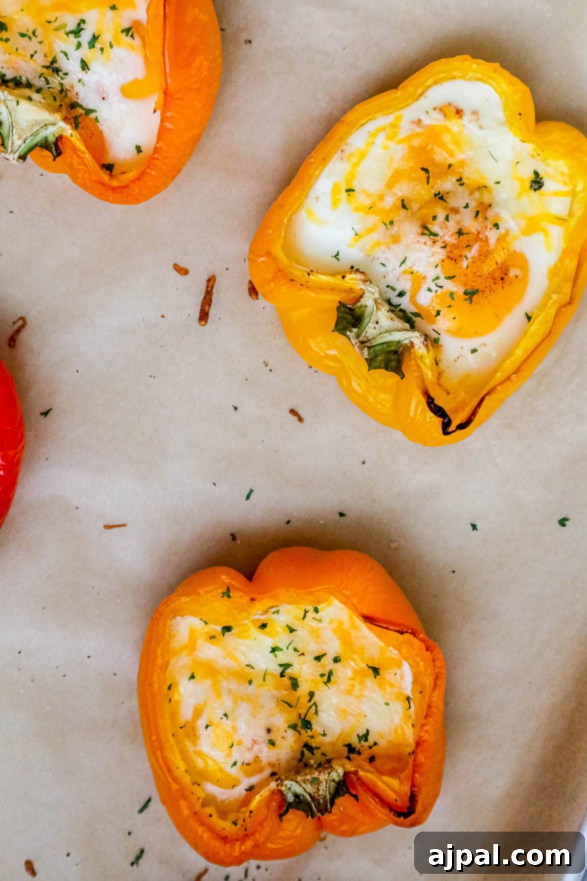 Bell Pepper Egg Bake 10 baked eggs inside halves of bell peppers with melted cheese and herbs on top