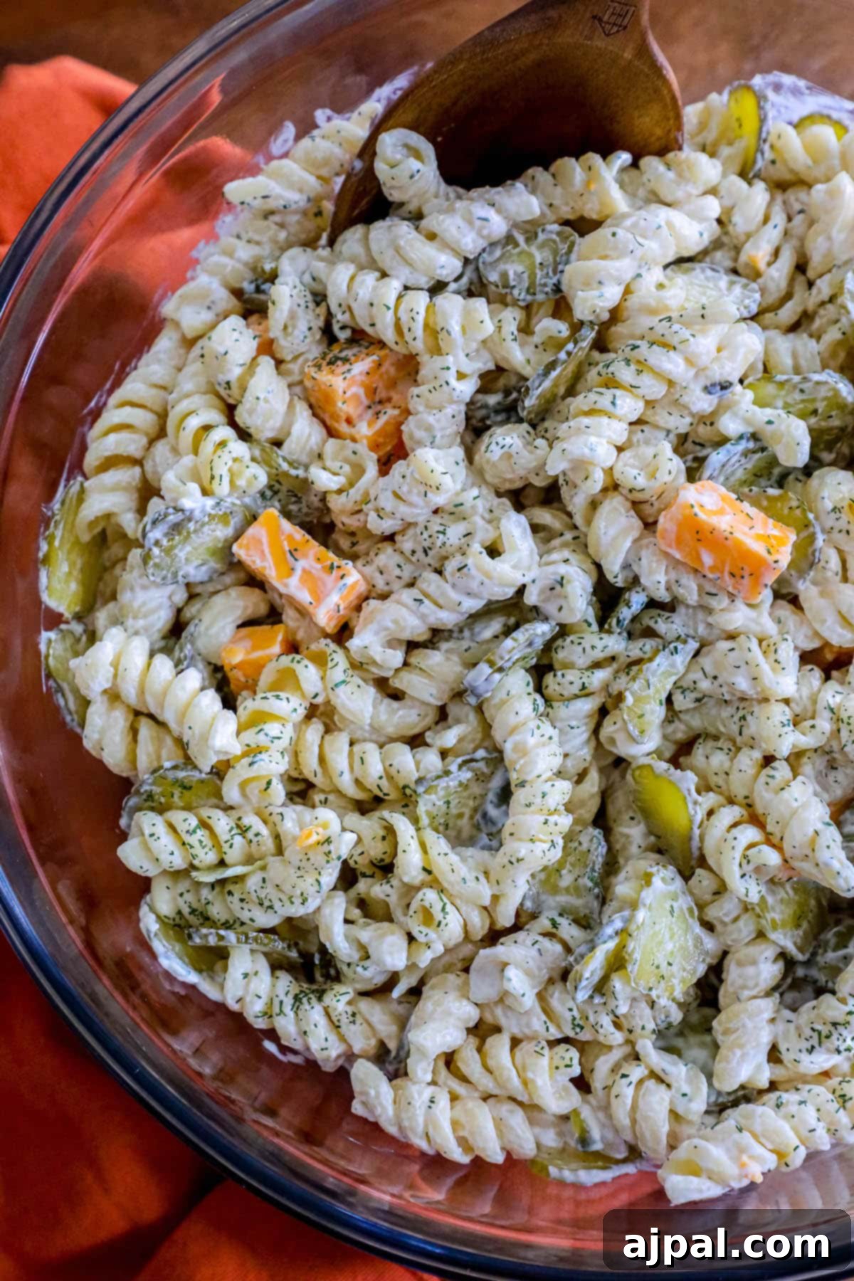 Tangy Dill Pasta Delight 8 Pasta salad mixed with chopped pickles and cheese tossed in dill mayonnaise sour cream dressing in a glass bowl, ready for serving.