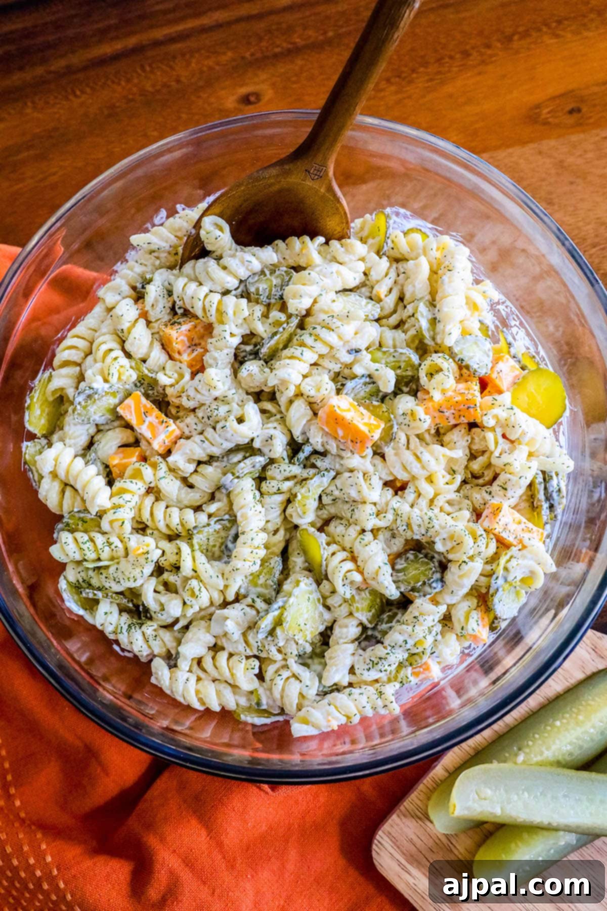 Tangy Dill Pasta Delight 3 Close-up shot of creamy dill pickle pasta salad with visible carrots and pickles, presented in a clear glass bowl.