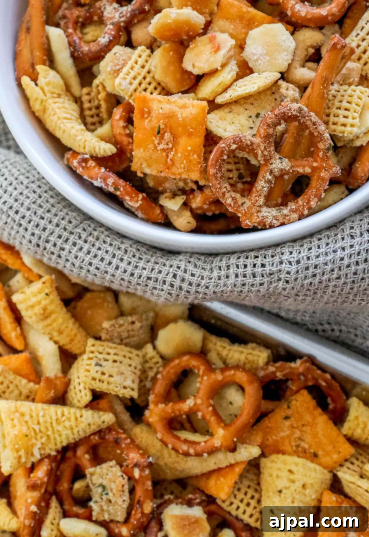 Assortment of pretzels, oyster crackers, cheese crackers, corn bugles, and corn Chex cereal seasoned with rich ranch seasoning, presented in a bowl.
