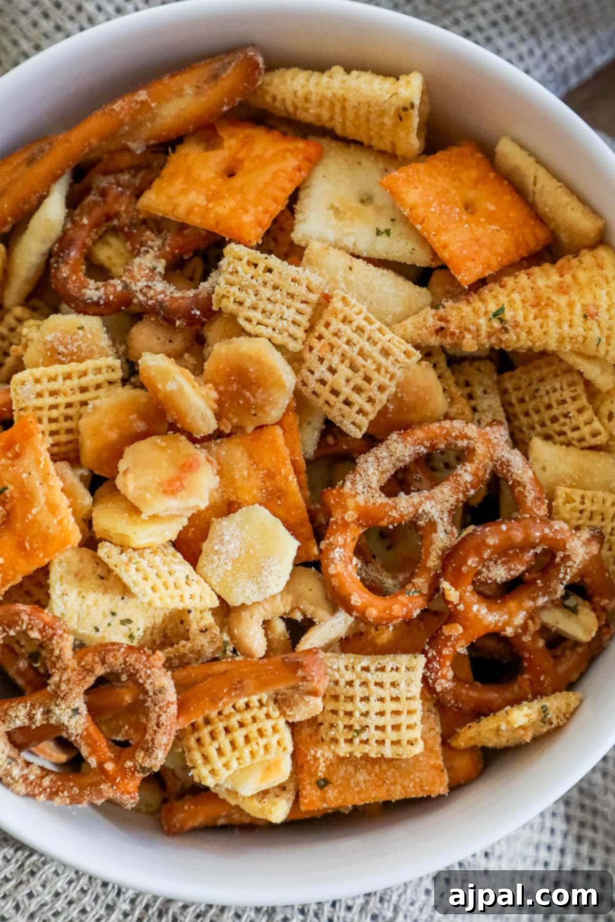 A pristine white bowl filled with ranch dressing-seasoned Chex Mix, featuring a delicious blend of crispy cheese crackers and corn cereal.
