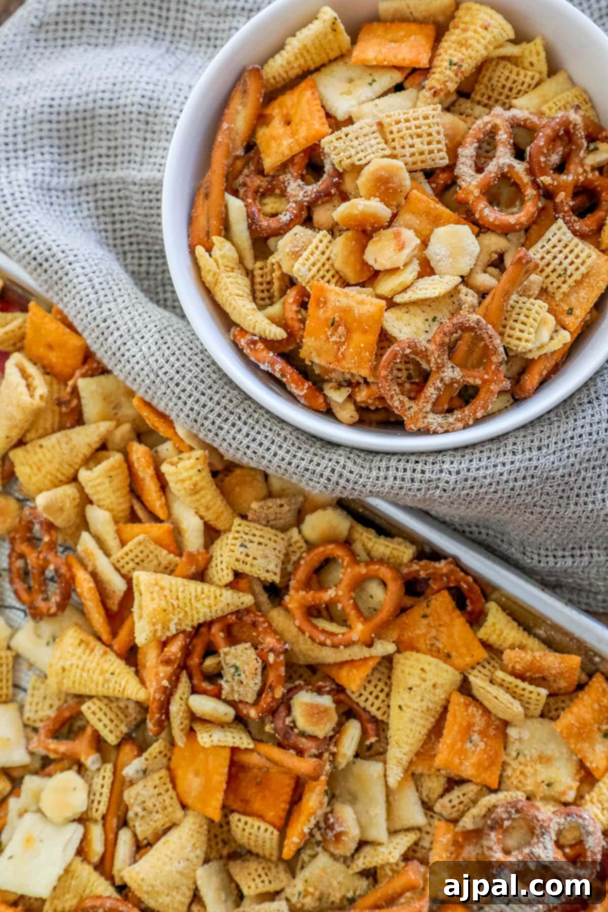 Ranch seasoned Chex Mix in a pristine white bowl, accompanied by another portion spread out on a baking sheet, showcasing its crunchy texture.
