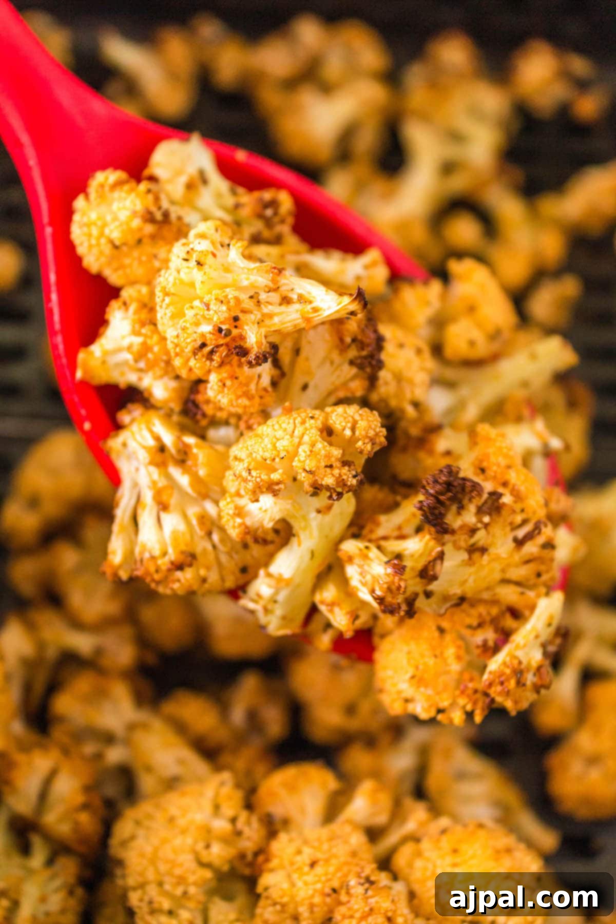 browned air fried cauliflower on a red spoon