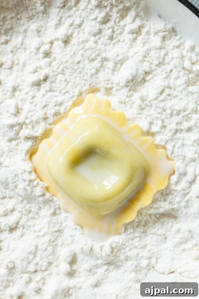 Ravioli, now coated in milk, being tossed in a bowl of flour