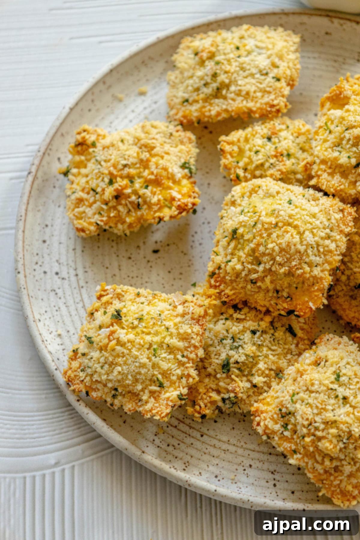 Crunchy baked breaded ravioli arranged on a white-speckled plate, ready to be served