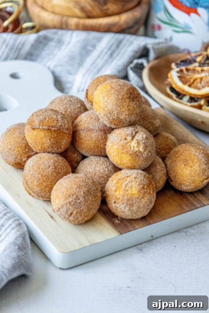 A close-up of baked cinnamon sugar donut holes artfully arranged on a cutting board, showcasing their appealing golden texture.