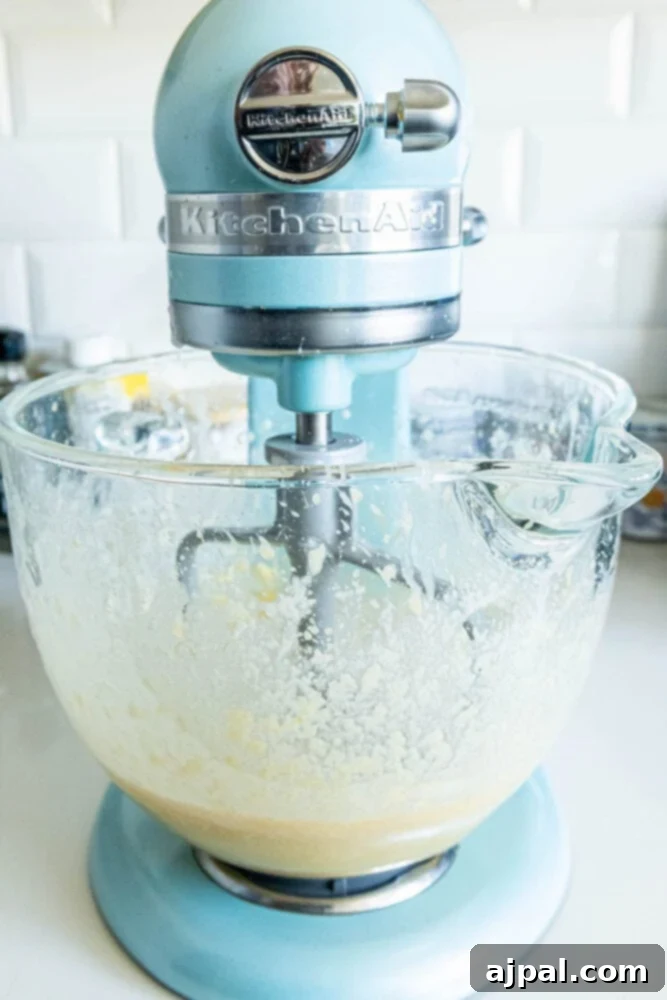 A stand mixer efficiently combining the donut hole batter, showing the smooth, creamy texture forming.