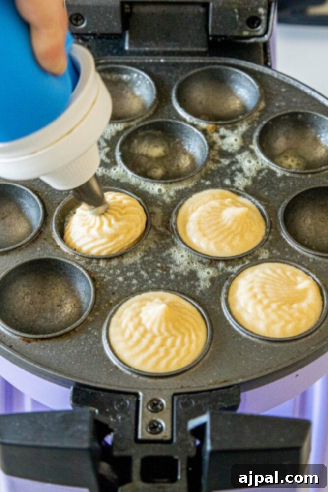 Donut hole batter being carefully piped into the molds of a cake pop machine for baking.