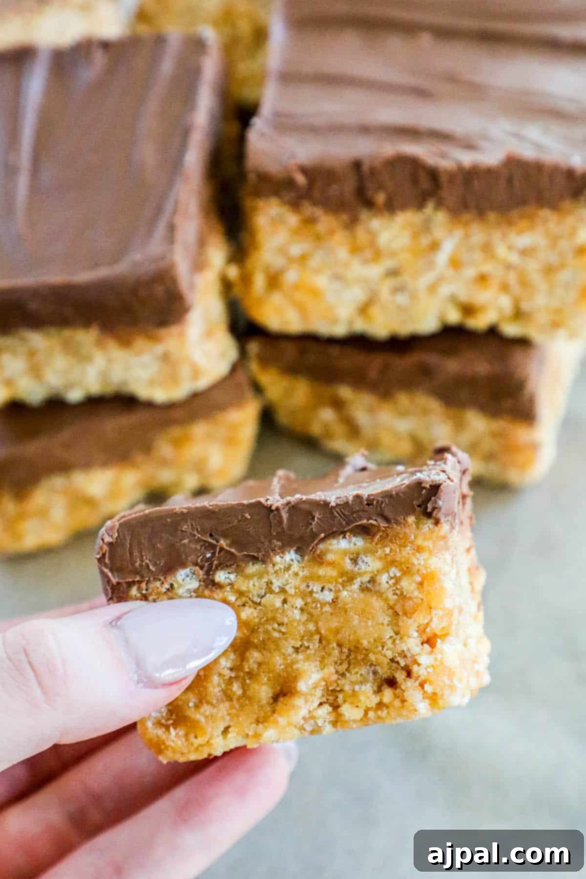 A person holding a scotcheroo, a delicious chocolate-coated oat bar.