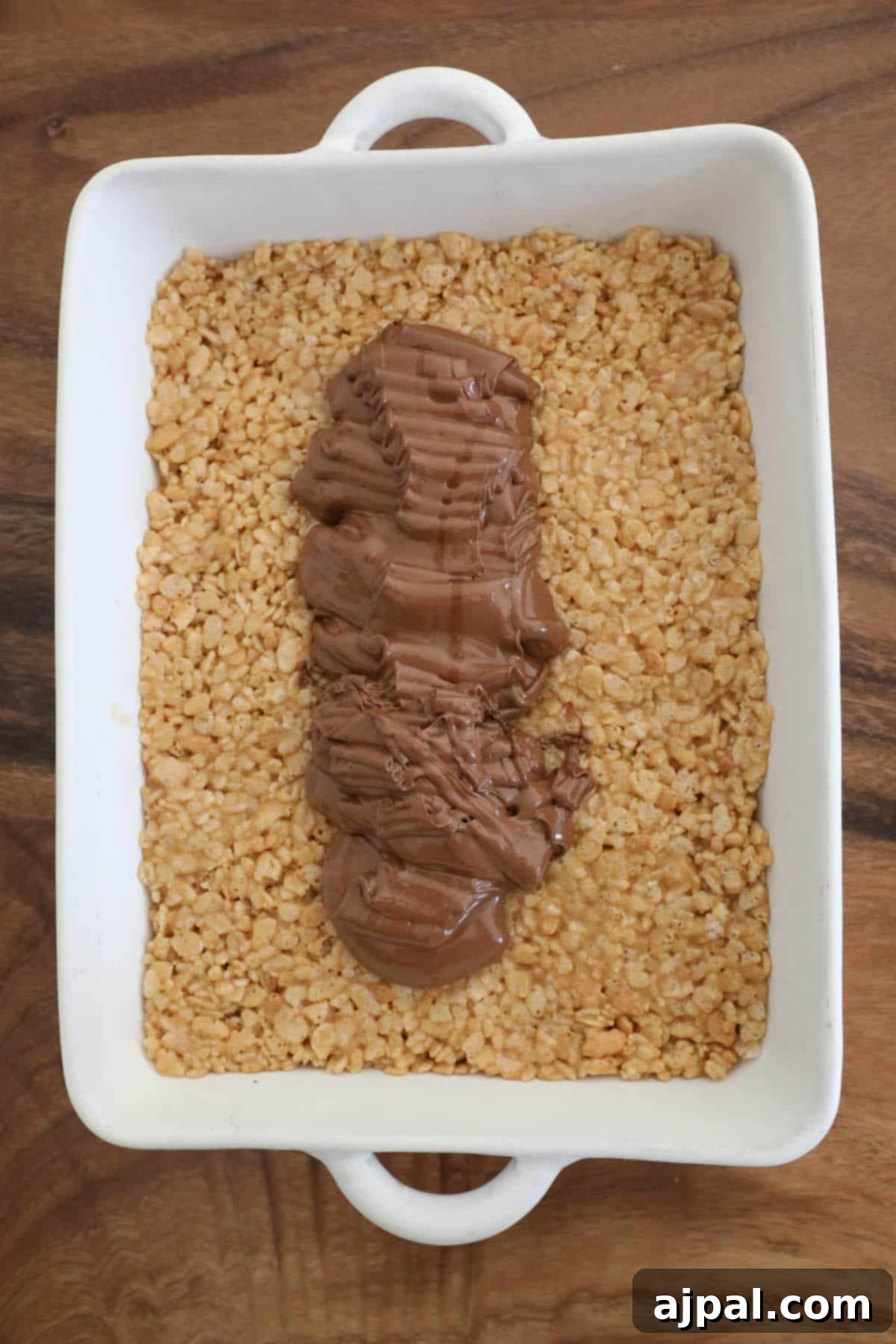 A square dish with scotcheroos and chocolate on top of it.