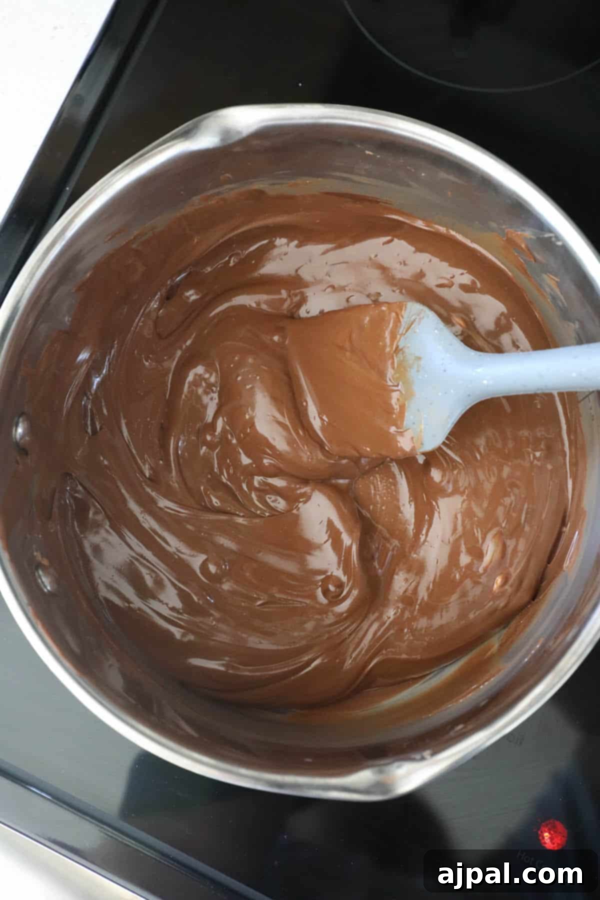 Melted scotcheroos in a pan with a spoon.