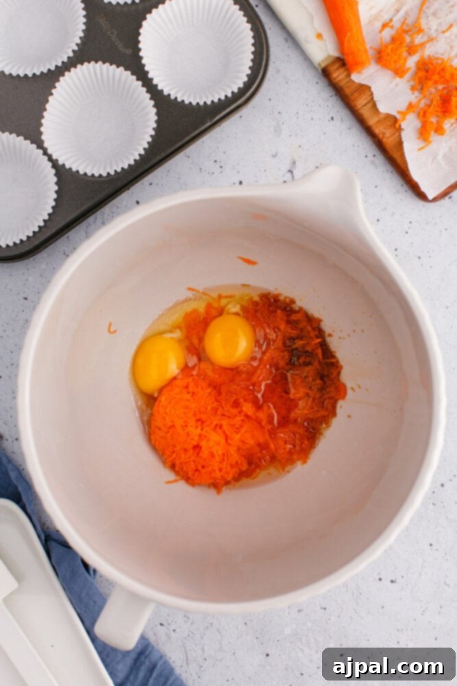 Effortless Carrot Muffins 7 A bowl filled with a delightful mixture of shredded carrots, beaten eggs, and brown sugar, perfectly blended for the muffin batter.