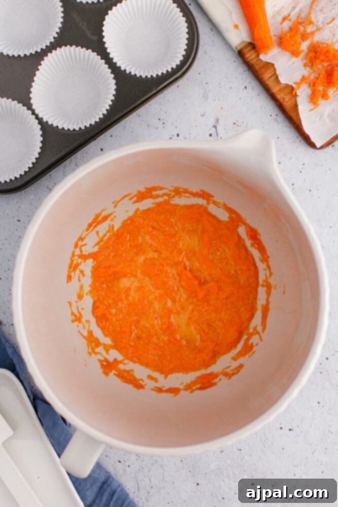 Effortless Carrot Muffins 8 The perfectly combined mixture of shredded carrots and beaten egg, showing the texture of the wet ingredients before flour is added.