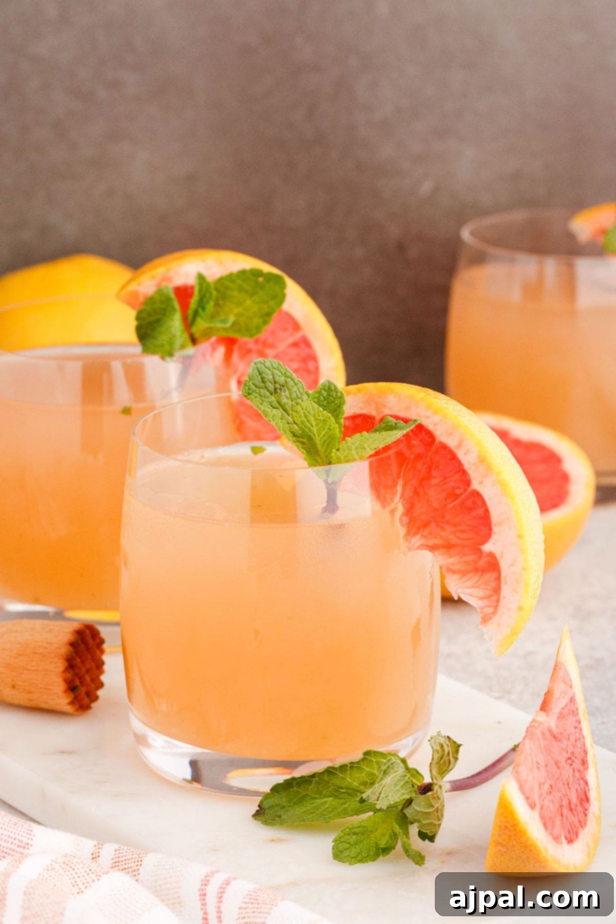 grapefruit mojito cocktail in a short glass with a sprig of mint and a slice of grapefruit on the side