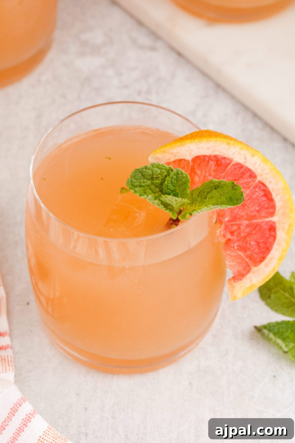 grapefruit mojito cocktail in a short glass with a sprig of mint and a slice of grapefruit on the side