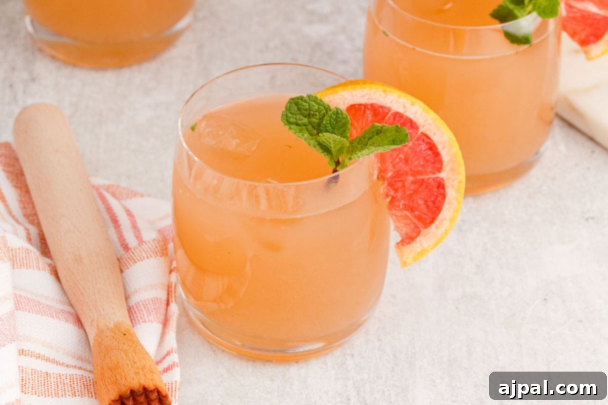 grapefruit mojito cocktail in a short glass with a sprig of mint and a slice of grapefruit on the side