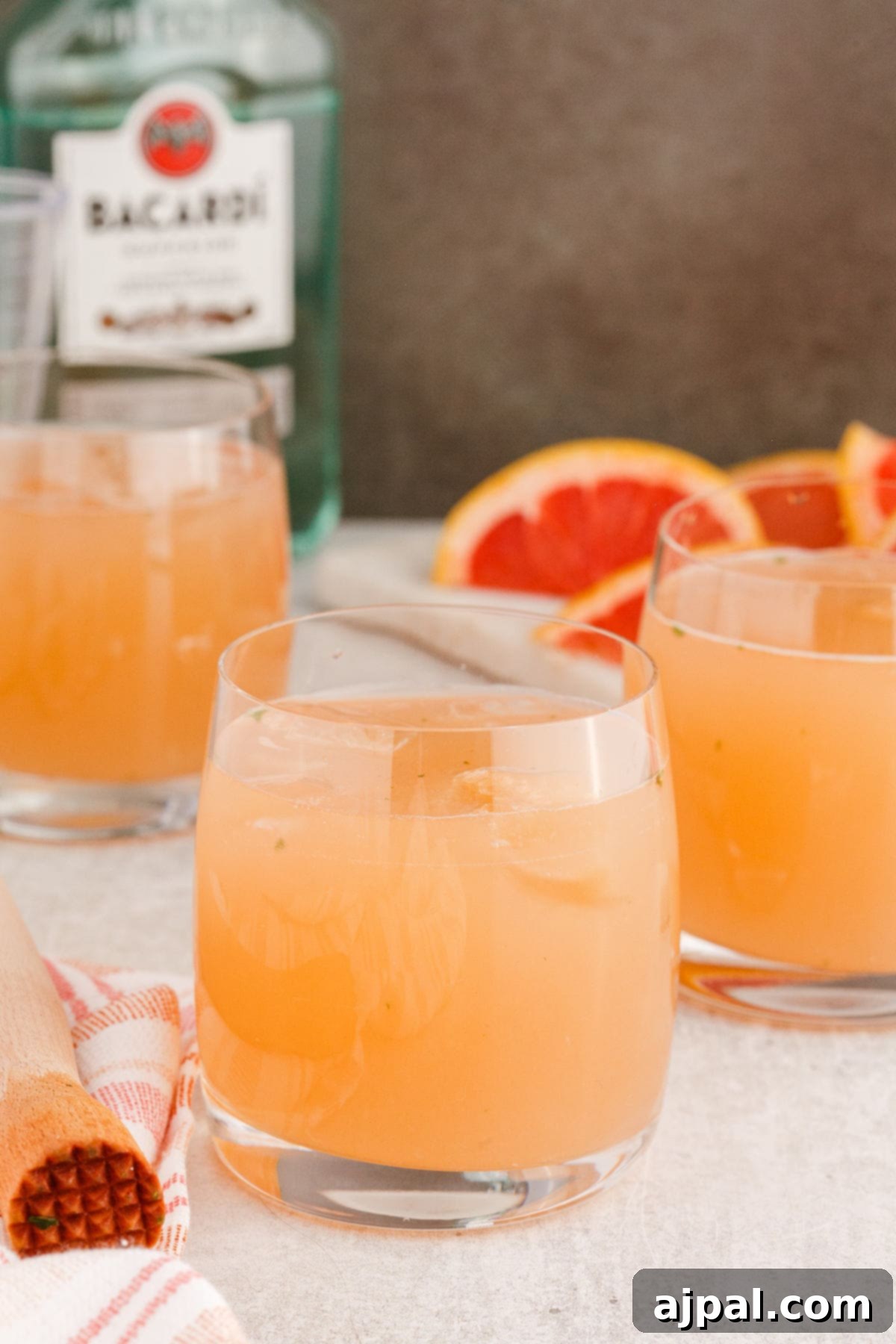 grapefruit mojito cocktail in a short glass with a sprig of mint and a slice of grapefruit on the side