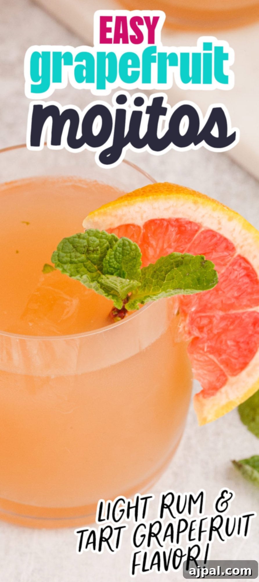 grapefruit mojito cocktail in a short glass with a sprig of mint and a slice of grapefruit on the side