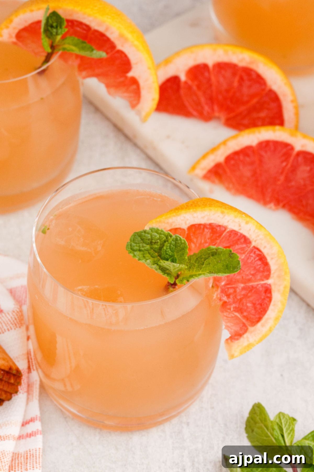 grapefruit mojito cocktail in a short glass with a sprig of mint and a slice of grapefruit on the side