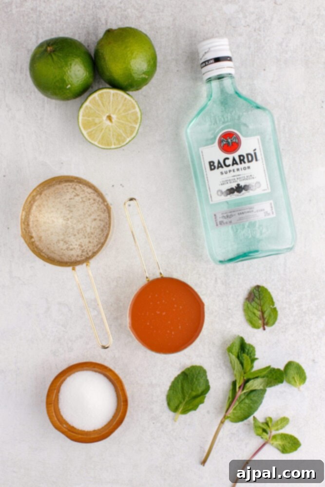 light rum, sugar, honey, lime, and grapefruit juice on a table with mint leaves