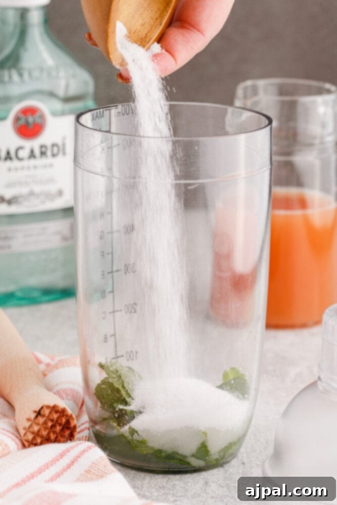 pouring sugar into a cocktail shaker with mint and lime juice