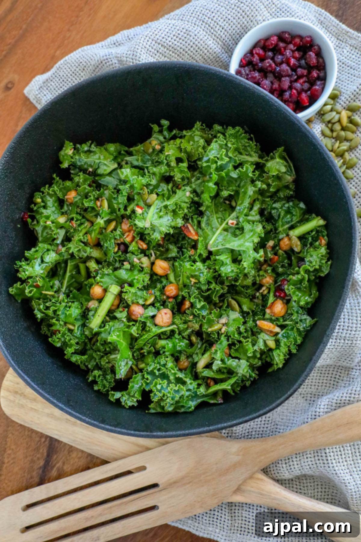 Mediterranean Chickpea Pomegranate Salad 2 Kale salad in a bowl with chickpeas, dried cranberries, pomegranate arils, pepitas, and dressing