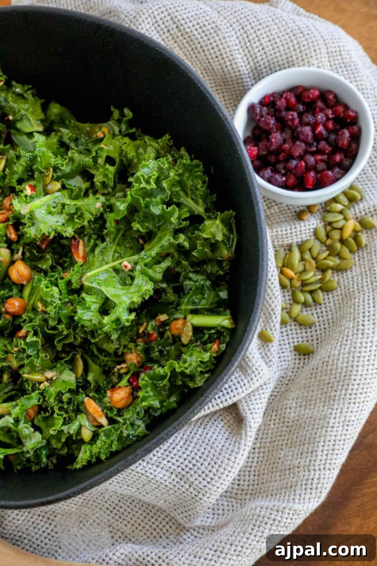 Jeweled Chickpea Pomegranate Salad 9 kale salad in a bowl with chickpeas, dried cranberries, pomegranate arils, pepitas, and dressing