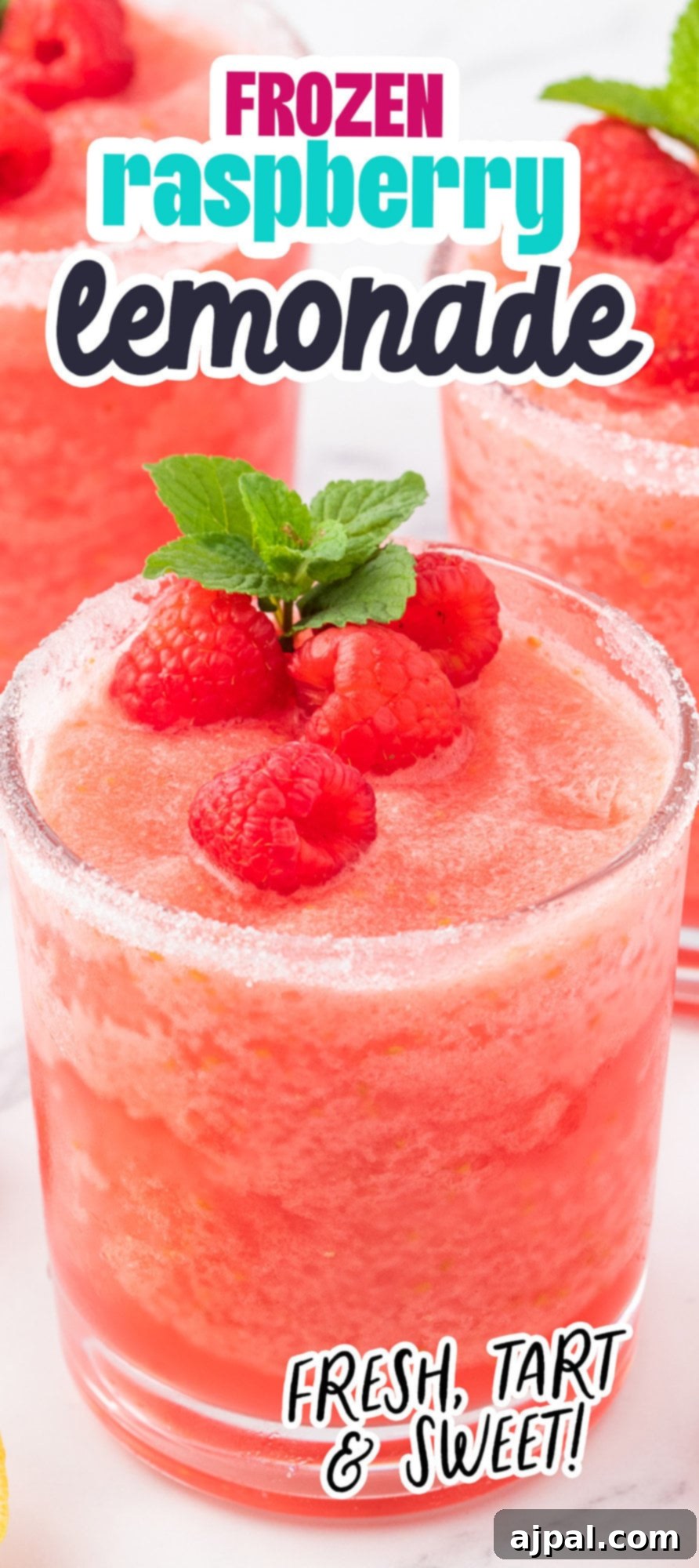frozen pink lemonade in a sugar rimmed glass with raspberries and a sprig of mint on top
