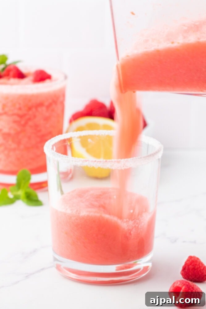 a blender pouring frozen pink lemonade in a cup