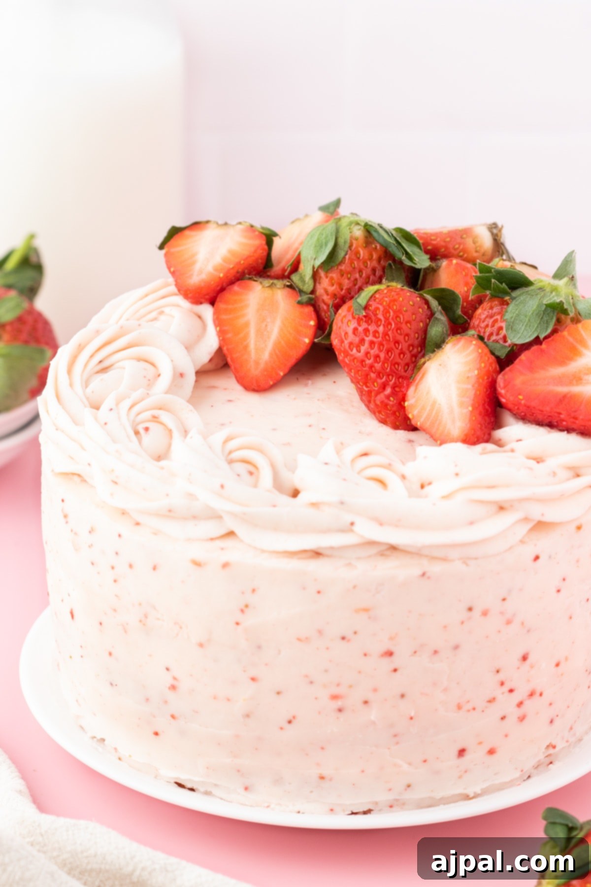 Fresh Strawberry Layer Cake 14 fresh sliced strawberries on a pink frosted cake with bits of strawberry in the whipped icing