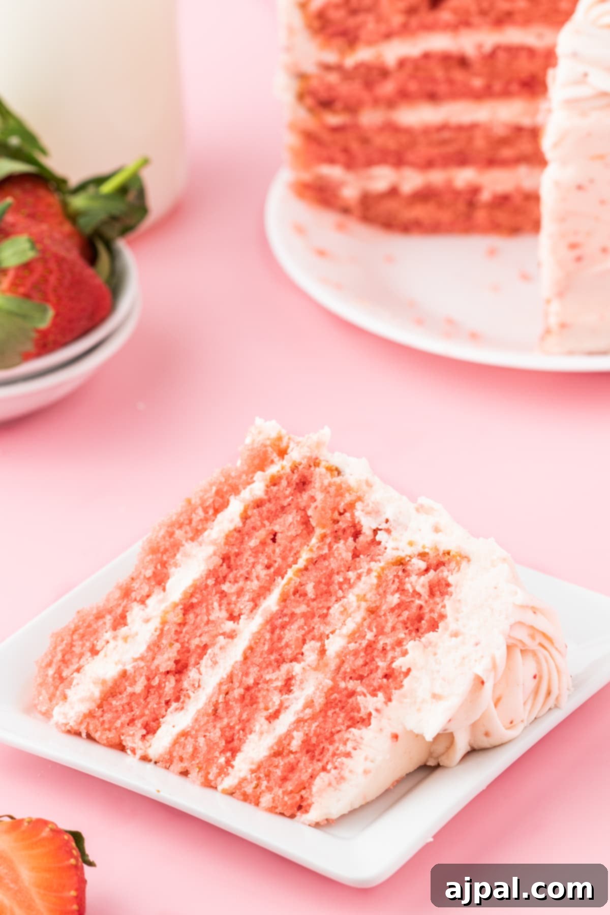 Fresh Strawberry Layer Cake 17 fresh sliced strawberries on a pink frosted cake with layers of whipped pink icing that has strawberry bits in it