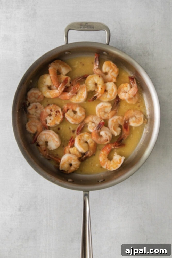 Effortless Shrimp Scampi 7 shrimp in a scampi butter sauce in a large pan
