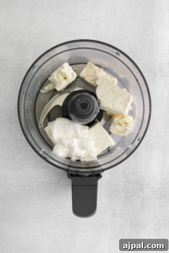 Feta cheese and garlic cloves in a food processor, ready to be blended into a creamy texture.